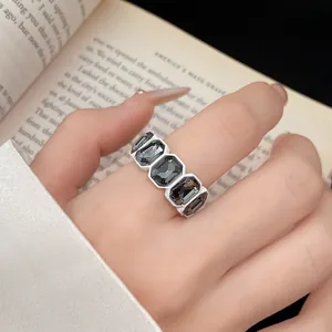 Primo piano di un anello rétro con cristalli esagonali indossato all'indice con libro