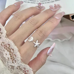 Detail showing the intricate shell and starfish design on a silver adjustable open ring