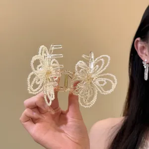 Close-up of an elegant Korean style pearl flower hair claw clip held by a female hand