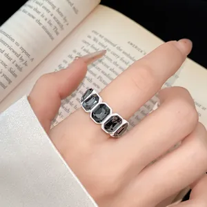 Primo piano di un anello esagonale stile vintage scuro con gemme nere indossato al dito