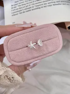 Detail view of silver starfish and seashell open ring on pink velvet jewelry box