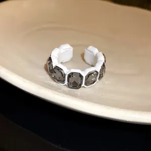 Primo piano di un anello aperto bianco vintage con cristalli scuri ottagonali.