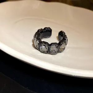 Dettaglio di un anello aperto stile retrò con strass esagonali su un piatto bianco