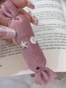 Detailed macro view of silver starfish and seashell rings on a pink velvet pillow