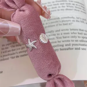 Close-up detail of silver starfish and seashell motifs on an adjustable open ring band