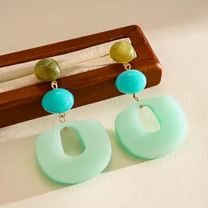 Macro view of colorful acrylic geometric earrings featuring mint green pendant details