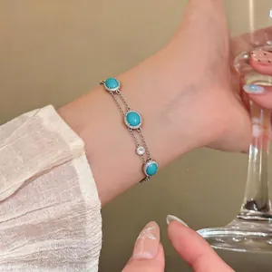 Elegant turquoise cabochon bracelet with silver double-chain and crystal accents on wrist