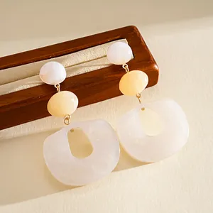 Macro view of white marble pattern acrylic geometric drop earrings on wooden stand