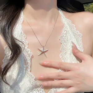 Elegant silver starfish pendant necklace worn by a model in a white lace halter top