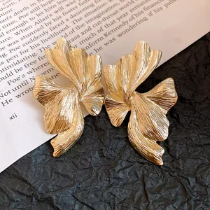 Dettaglio ravvicinato di orecchini d'oro irregolari con texture geometrica unica