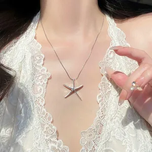 Detail view of a minimalist silver starfish pendant necklace on an elegant lace collar.