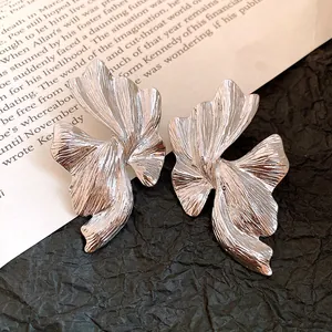 Primo piano di orecchini geometrici irregolari in argento con finitura testurizzata.