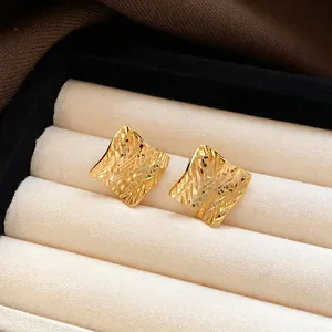Close-up of vintage-style square gold stud earrings with textured surface in jewelry box