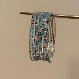 Nahaufnahme mehrlagiger elastischer Armbänder mit blauen und klaren Strasssteinen.