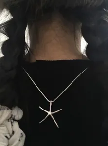 Back view detail of a minimalist silver starfish pendant necklace worn on a model