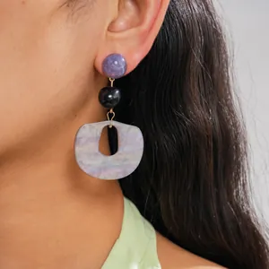 Macro view of unique geometric acrylic drop earrings with purple and marbled textures