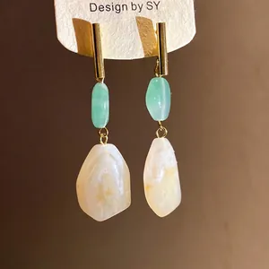 Elegant resin geometric drop earrings with gold-tone accents on a warm golden background.