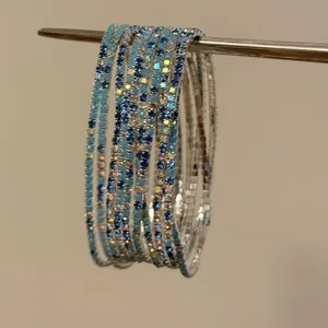 Detailansicht schlanker elastischer Armreifen mit blauen und klaren Kristallen.