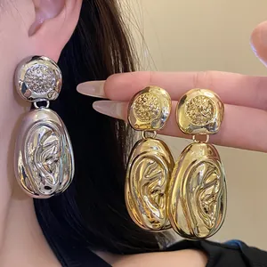 Detail view showing the elegant gold and silver pleated texture of these statement drop earrings