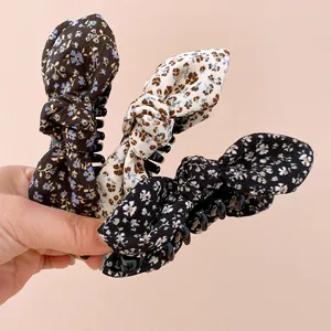Gros plan de trois pinces à cheveux à nœud en tissu floral aux motifs vintage élégants
