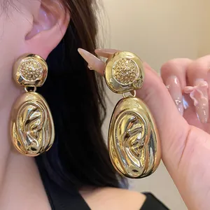Close-up of gold chunky textured drop earrings showing elegant wrinkled design detail.