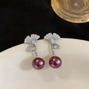 Detalle de pendientes hoja de ginkgo con circonitas y elegantes perlas rojo vino en plato