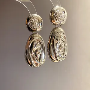 Macro detail showing the wrinkled metallic texture of silver droplet pendant earrings.