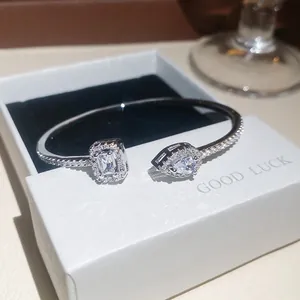 Primo piano di un elegante bracciale rigido aperto con zirconi a smeraldo e goccia