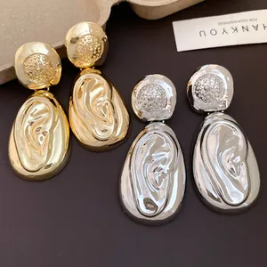 Elegant gold and silver waterdrop earrings with wrinkled metallic texture in close-up.
