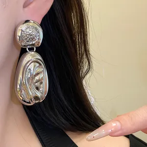 Close-up of silver drop earrings with a unique wrinkled metallic texture