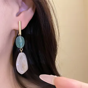 Detailed close-up of retro geometric resin drop earrings with green and white stones.