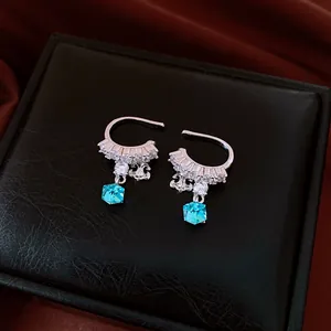 Detailed shot of silver ear cuff with sparkling zircons and square blue crystal pendant