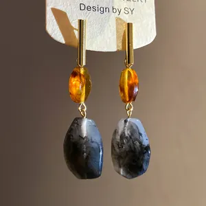 Close-up of resin drop earrings with amber beads and grey marble patterns