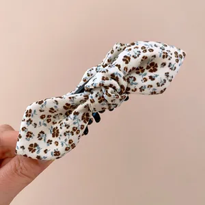 Détail d'un nœud en tissu blanc avec imprimé floral sur une pince à cheveux élégante