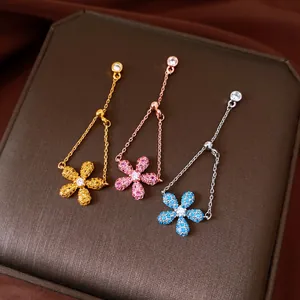 Tre anelli regolabili con fiori di zircone colorati su una scatola di gioielli marrone.
