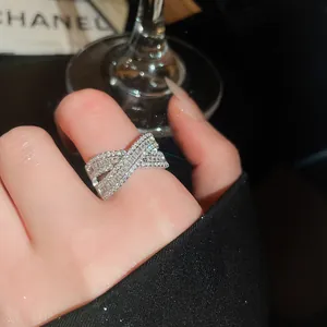 Primo piano di un anello a incrocio in argento con pietre di zircone su un dito femminile