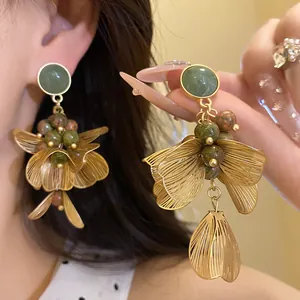 Detailed view of elegant gold tassel earrings featuring green stones and wire petals