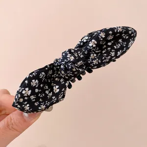 Gros plan d'une pince à cheveux avec un nœud en tissu floral noir et des dents solides