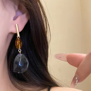 Detailed view of geometric resin drop earrings with amber beads and smoky pendants