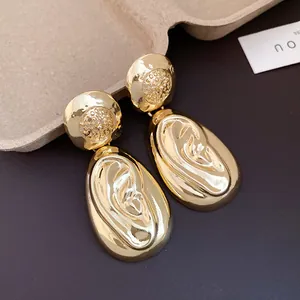 Close-up of luxury gold anatomical ear-shaped drop earrings with a vintage textured finish