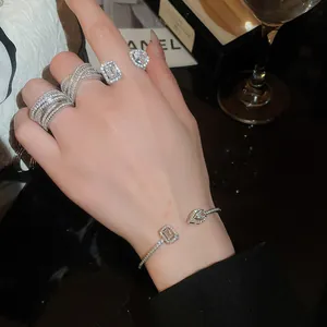 Primo piano di un elegante anello aperto in argento con zirconi a forma di quadrato e goccia
