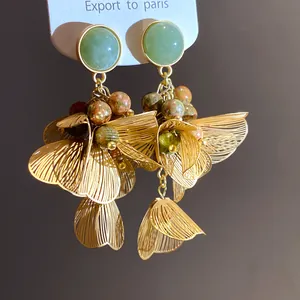 Macro view of elegant floral tassel earrings with green stones and gold wire petals