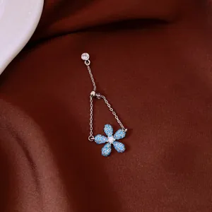 Dettaglio macro di un anello d'argento regolabile con fiore in zircone blu su tessuto marrone