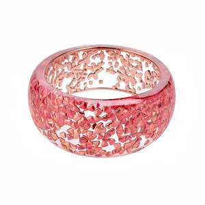 Elegante bracciale rigido in resina rosa con inserti metallici a mosaico lucenti
