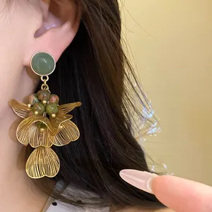 Close-up of gold hollow petal tassel earrings with colored natural stone beads
