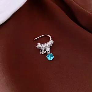 Macro view of silver-tone non-pierced ear cuff featuring zircon stones and a blue crystal