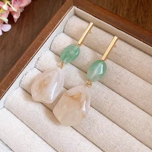 Elegant geometric resin earrings with green and cream marble pendants on gold bars.
