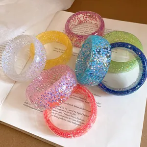 Primo piano dettagliato di bracciali in resina olografica colorata su un libro aperto