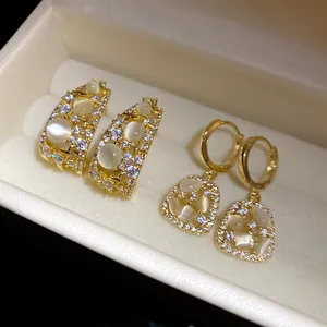 Close-up of elegant gold-plated zircon earrings with cat-eye stone details in a box
