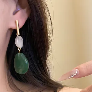 Close-up shot of vintage resin drop earrings featuring green and white geometric stones.